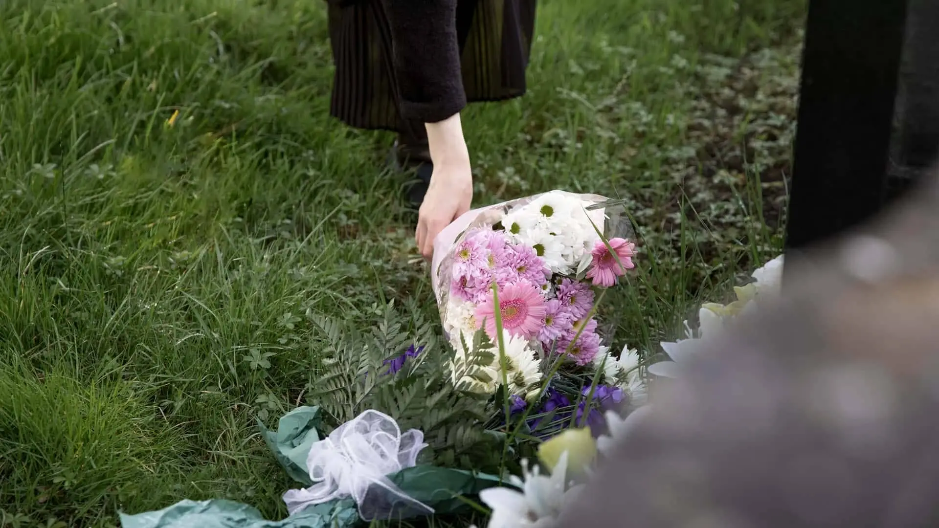 Persona de luto deposita un ramo de flores en una tumba en el cementerio. Homenaje y recuerdo a un ser querido fallecido.