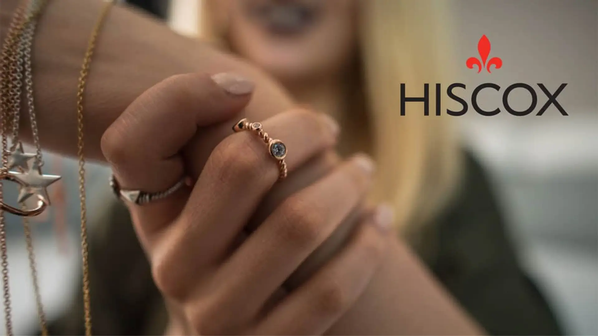 Manos con joyas de oro junto al logotipo de Hiscox para representar el seguro de objetos de valor y coleccionismo.