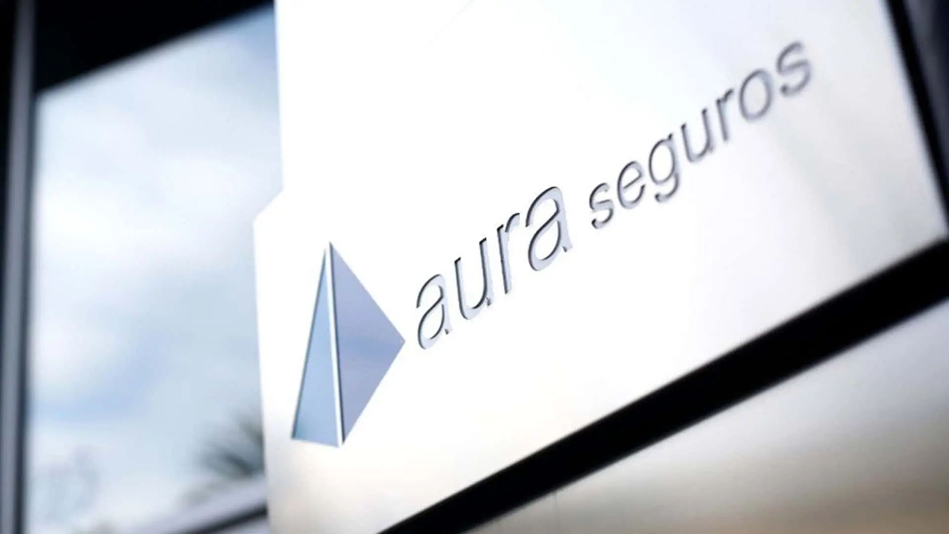 Logotipo de Aura Seguros en la fachada de una oficina.