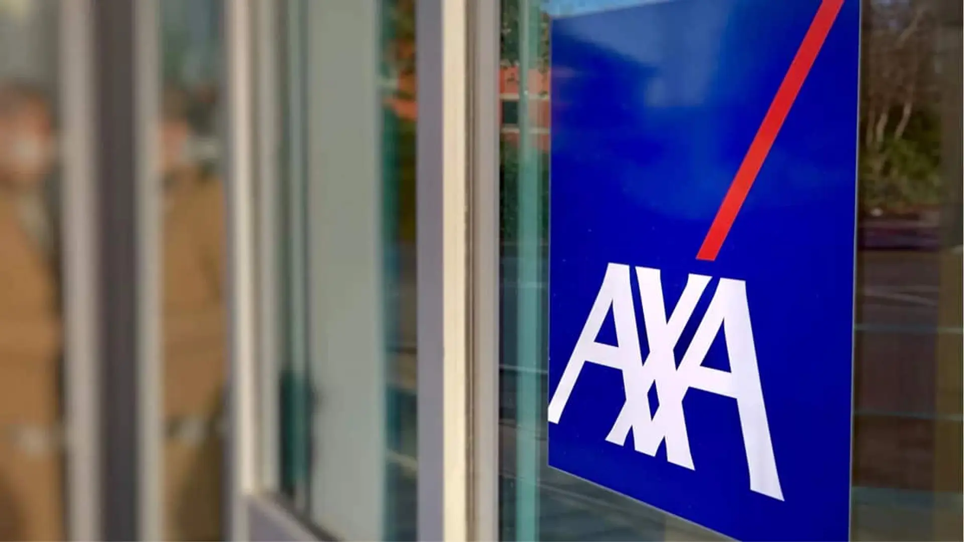 Logotipo de AXA en la puerta de cristal de una oficina de la aseguradora.