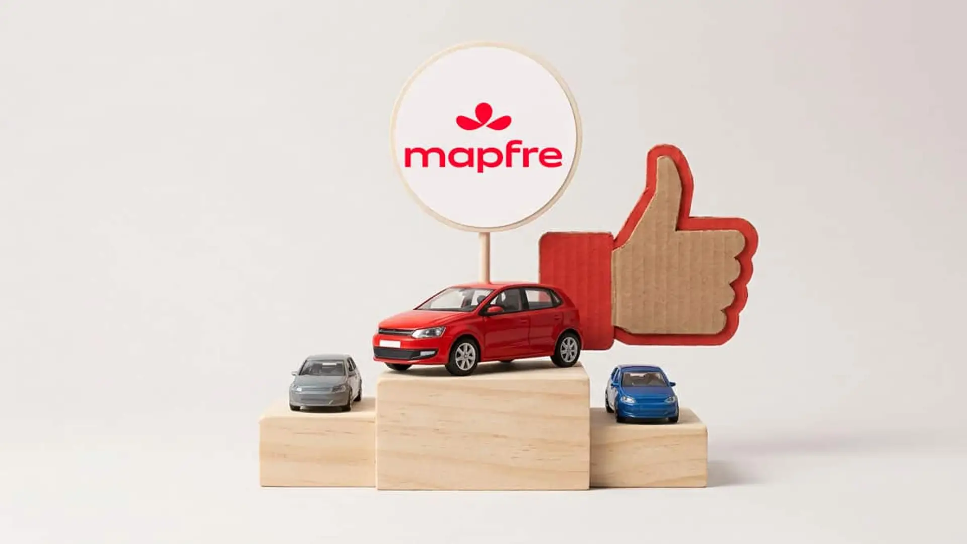 Tres coches sobre un podio junto al logotipo de Mapfre y un símbolo de pulgar hacia arriba