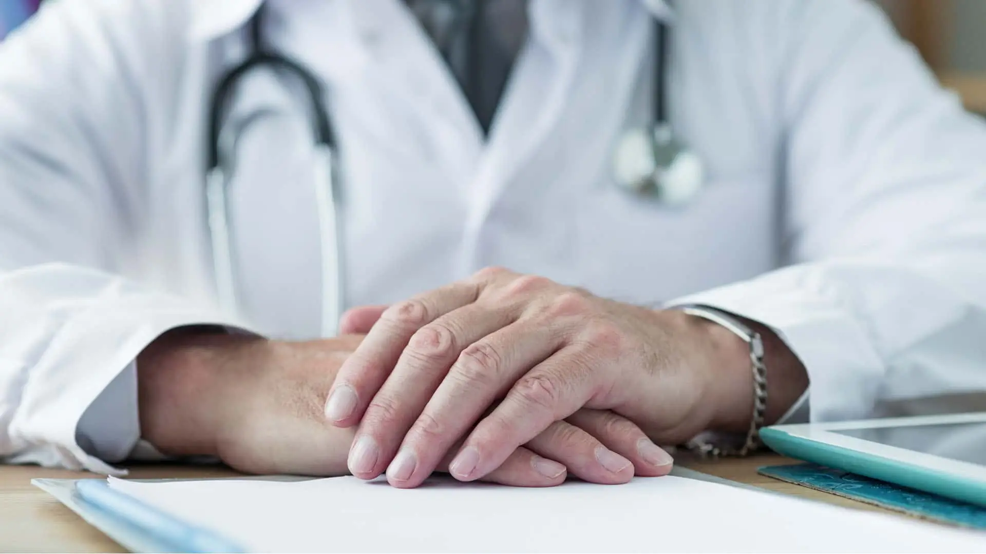 Primer plano de un médico con bata y estetoscopio en su consulta. Atención médica, diagnóstico y seguros de salud.
