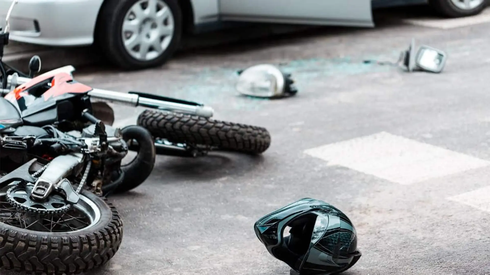 Salud y Motos lideran las subidas de las primas de seguros, mientras Autos y Hogar frenan precios en busca de estabilidad Motocicleta accidentada en la calzada tras un siniestro de tráfico, con casco y restos en el asfalto junto a un coche.