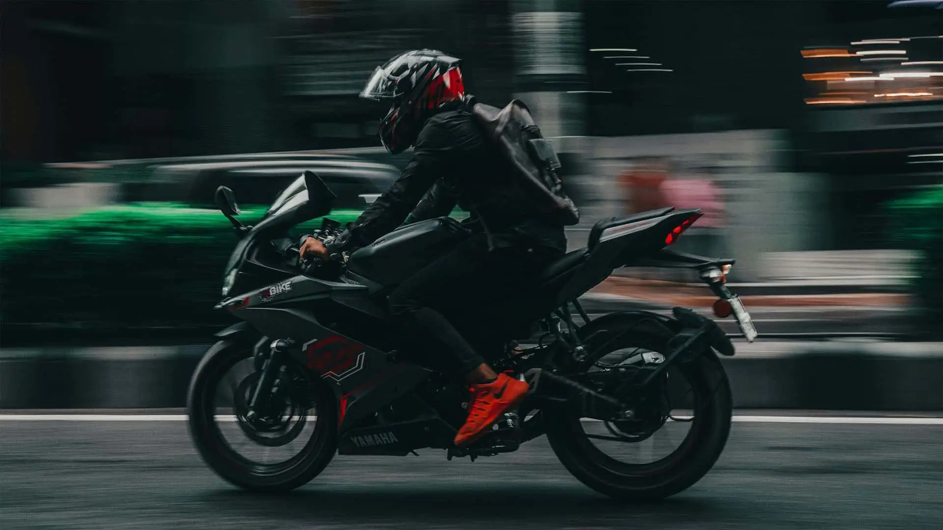Motociclista con casco conduciendo una moto deportiva a gran velocidad por la ciudad.