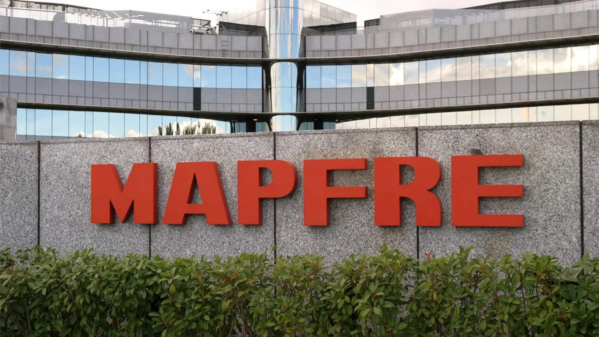 Mapfre lanza una plataforma para favorecer la retribución flexible en pymes Entrada principal de una sede de Mapfre con su logotipo rojo sobre una pared de piedra.