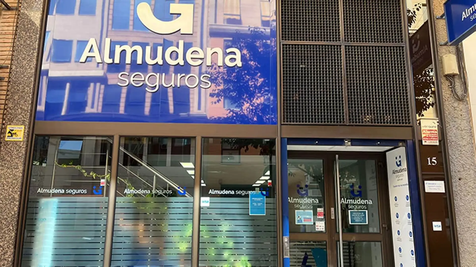 Almudena Seguros gana un 10,5% más con el ramo de decesos como palanca de crecimiento Fachada de una oficina de Almudena Seguros con cartelería corporativa azul para atención al cliente y gestión de pólizas.