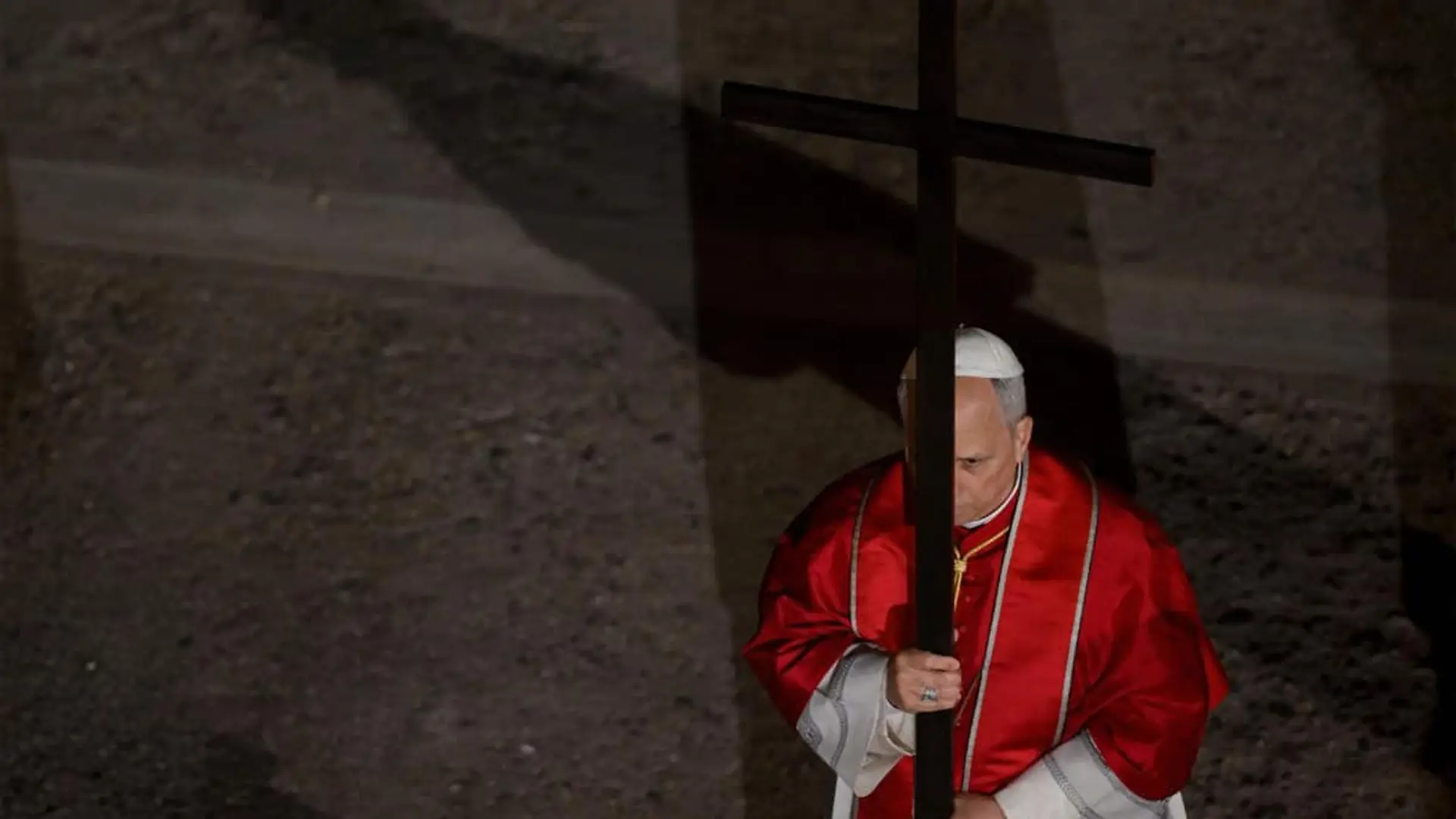 El Papa León XIV carga una cruz durante la celebración del vía crucis.