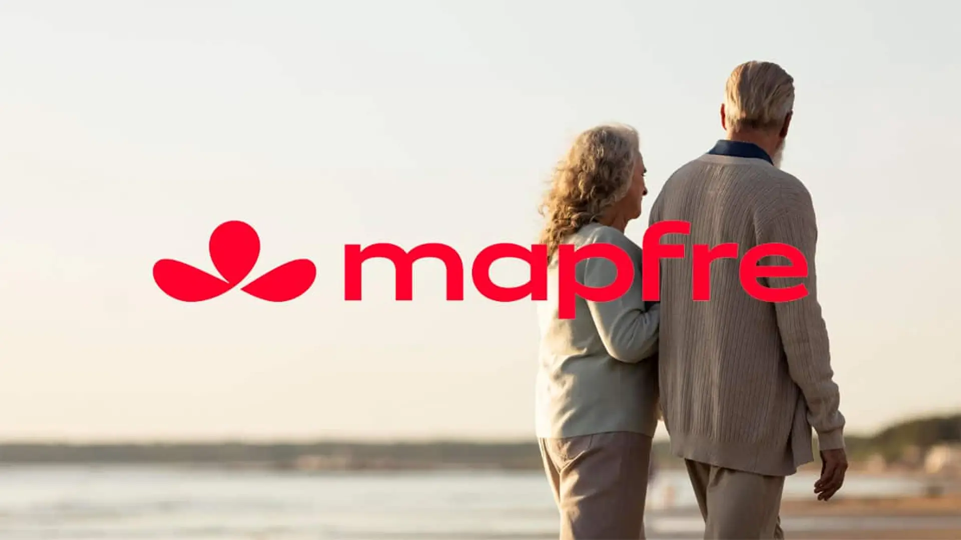 Pareja mayor caminando junto al mar con el logotipo de Mapfre sobre la imagen