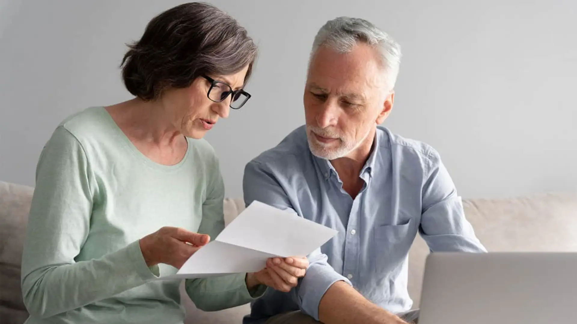 Pareja de jubilados revisando documentación de su seguro de decesos.