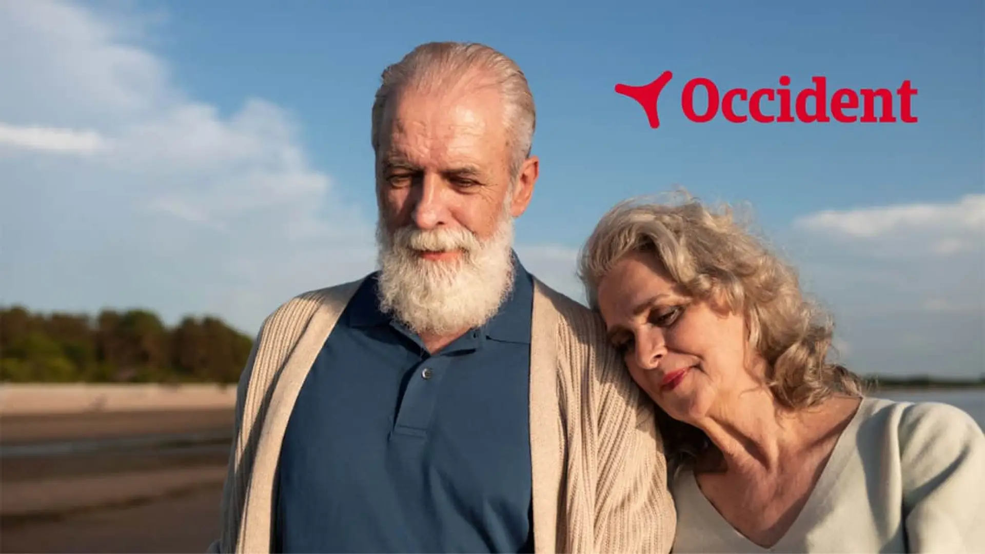 Pareja sénior paseando por la playa junto al logo de Occident para representar la seguridad y el ahorro en la jubilación.