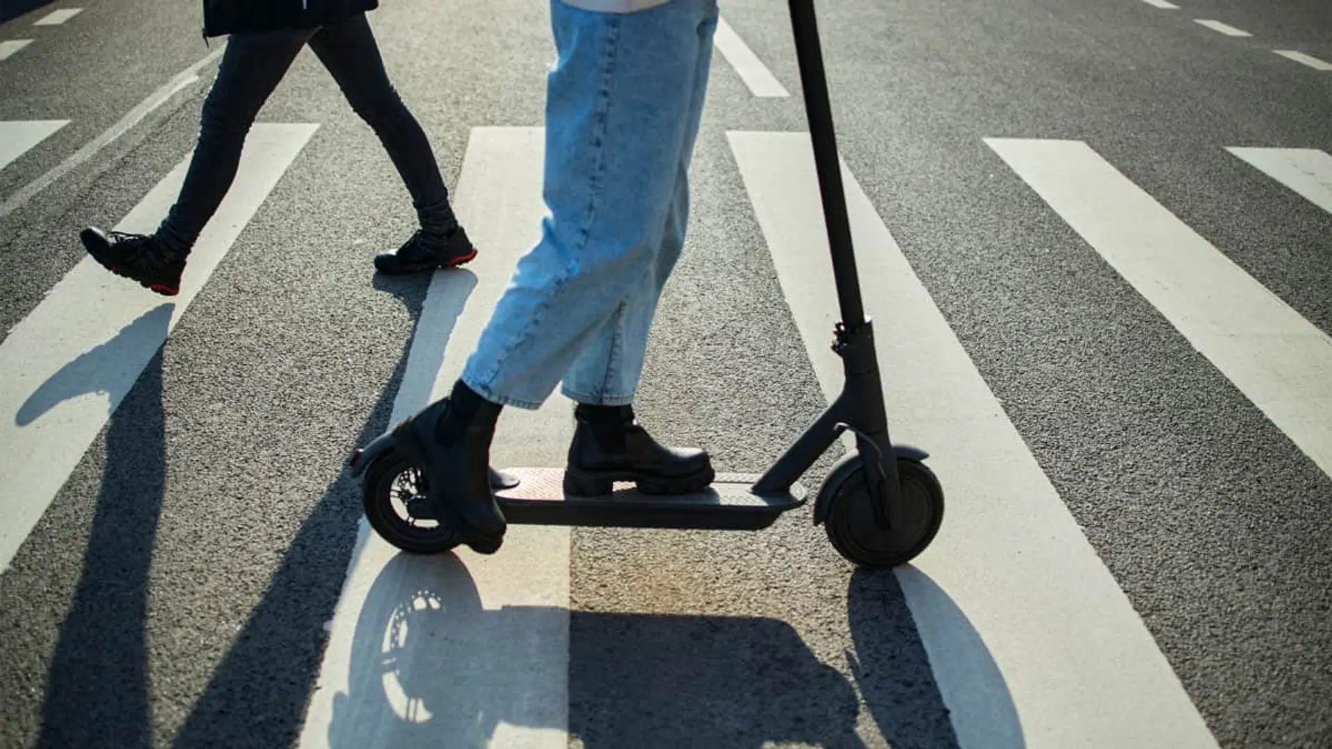 Persona en patinete eléctrico cruzando un paso de peatones, clave en la movilidad urbana y normativa de seguridad vial.