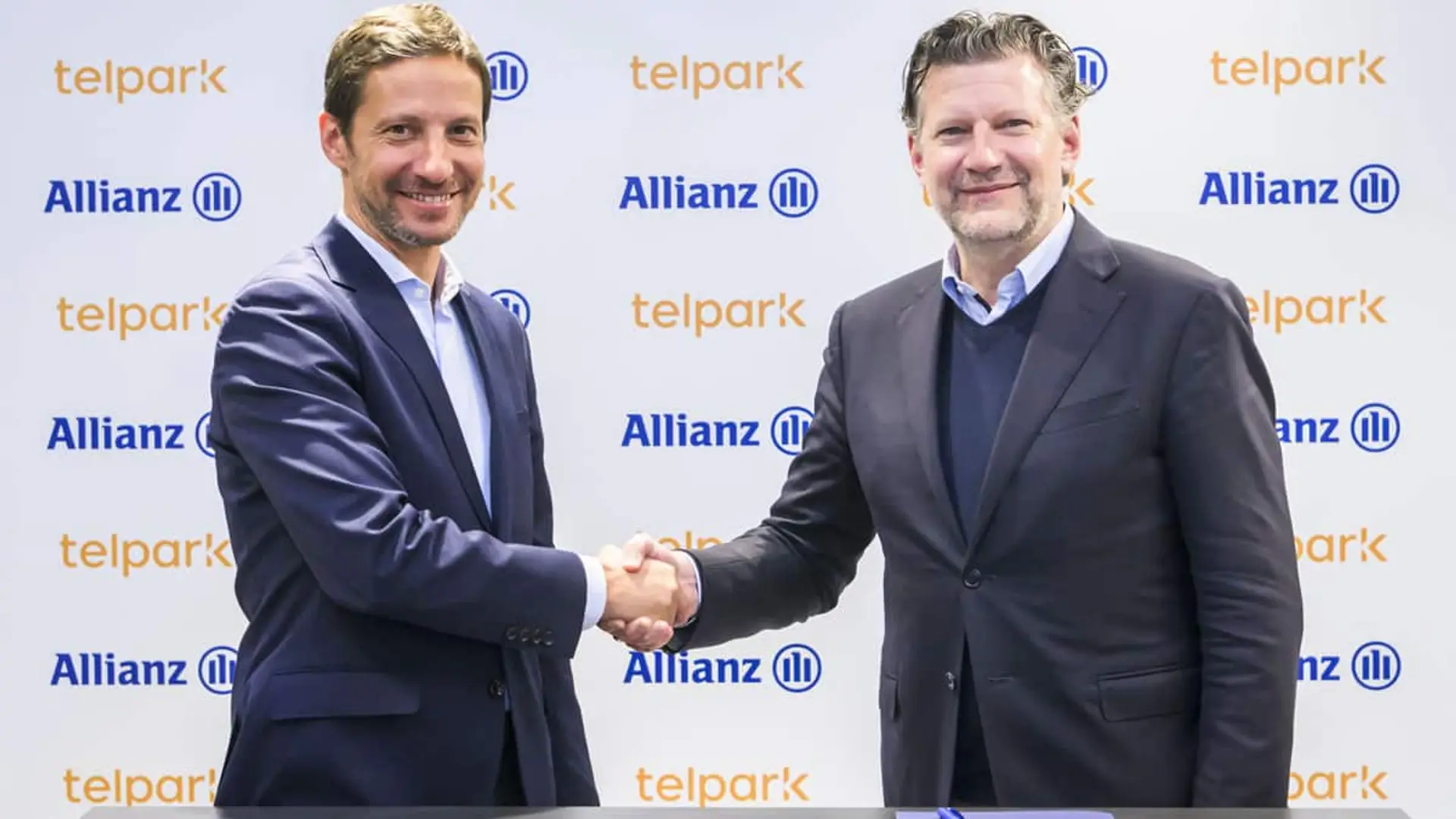 Por qué Allianz se alía con Telpark (y no es solo para vender más seguros) Dos representantes de Allianz y Telpark estrechándose la mano delante de un panel con los logotipos de ambas marcas
