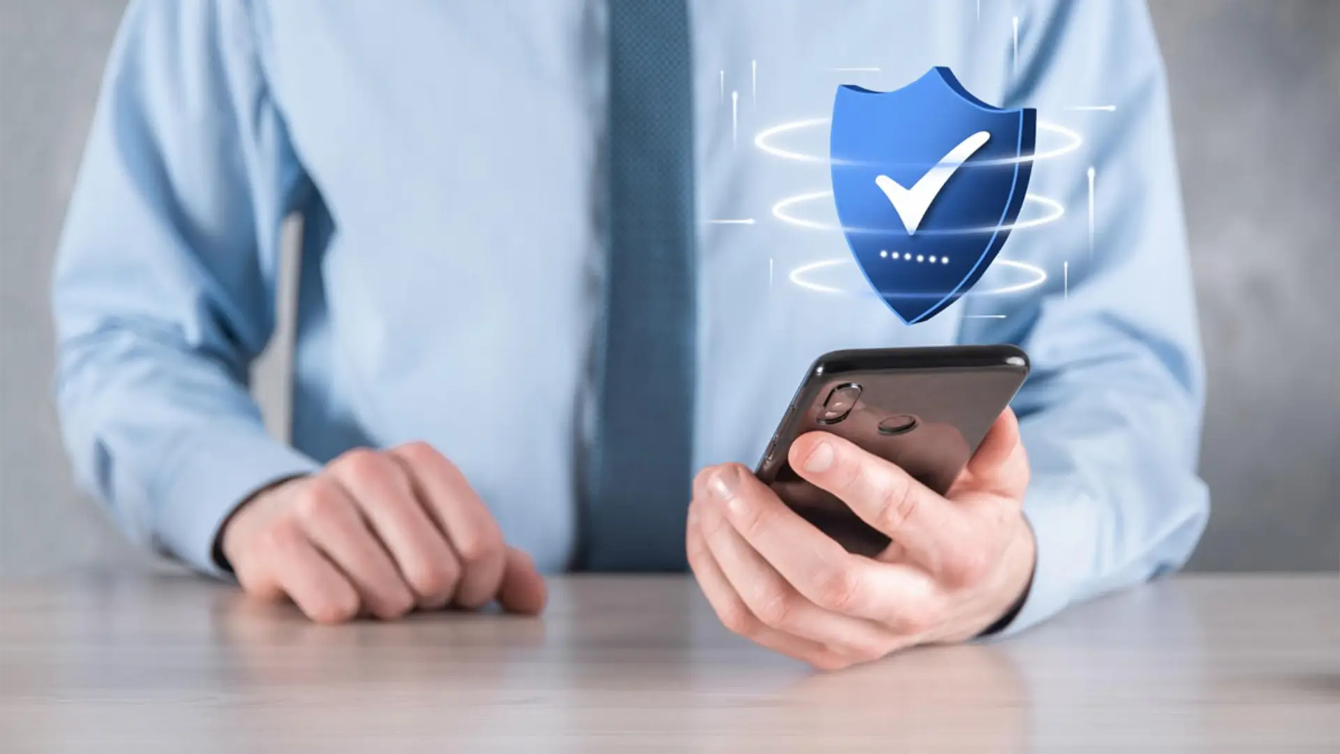 Los seguros para móviles se quedan cortos ante el nuevo riesgo digital: identidad y datos bancarios en juego Icono de escudo azul sobre smartphone simbolizando la protección antivirus o ciberseguridad.