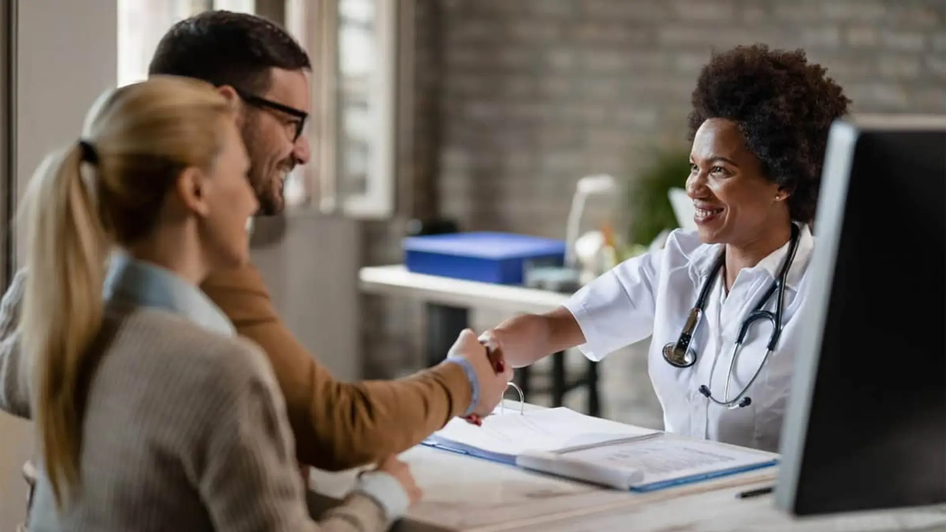 Aegon mejora sus seguros de salud: incorpora coberturas pioneras de cara a 2026 Doctora sonriente estrecha la mano a un paciente en su consulta.
