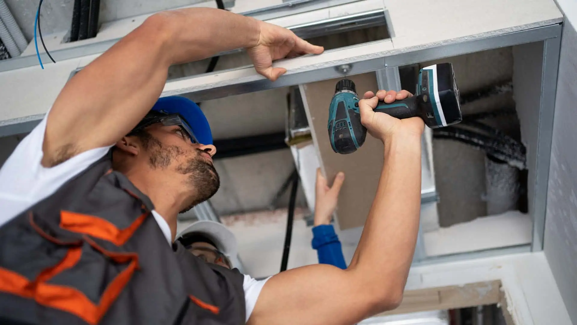 Trabajador reparando el techo de una vivienda con un taladro eléctrico.