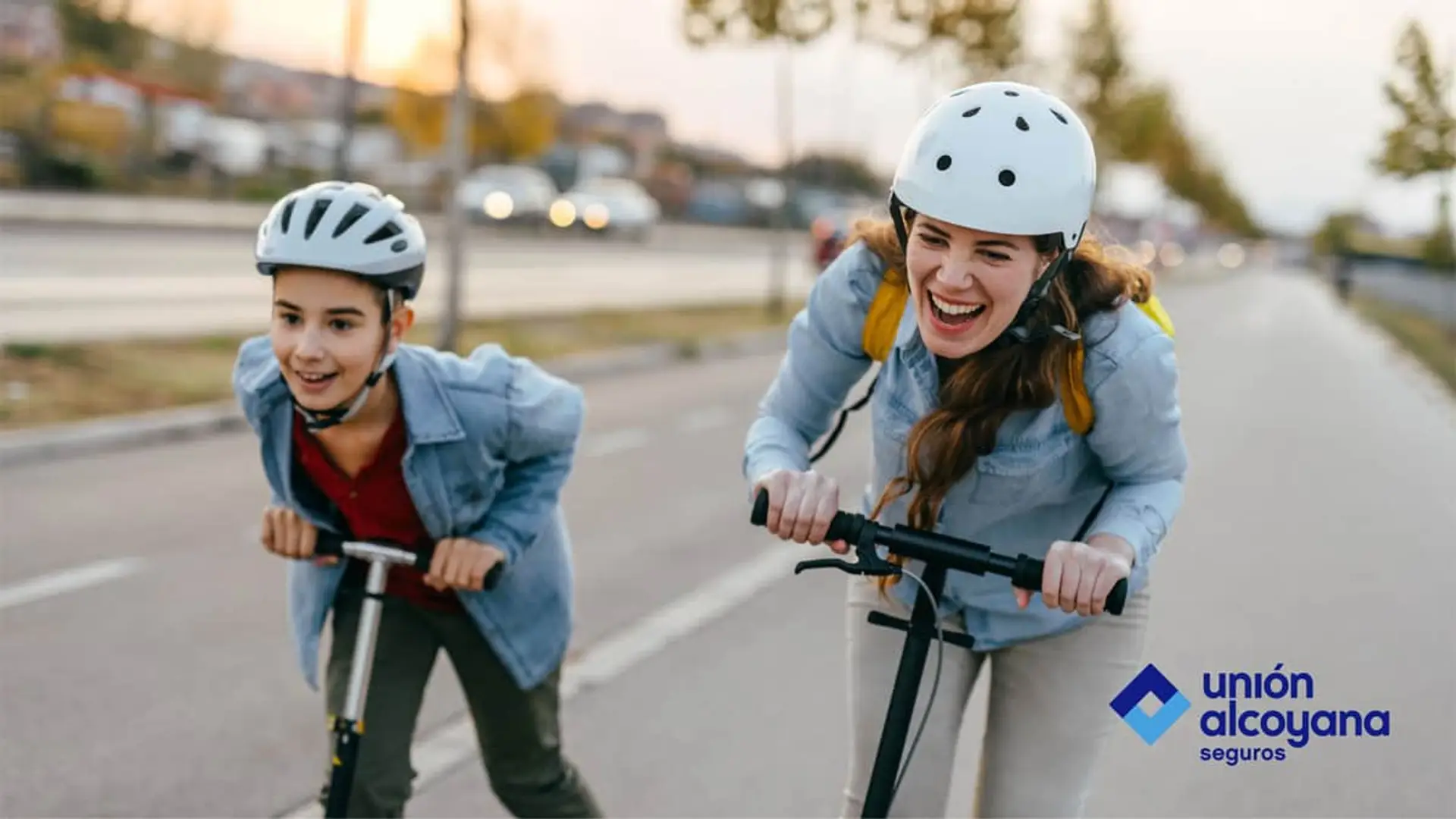 Mujer y niño con casco en patinete eléctrico junto al logo de Unión Alcoyana Seguros, especialistas en movilidad.