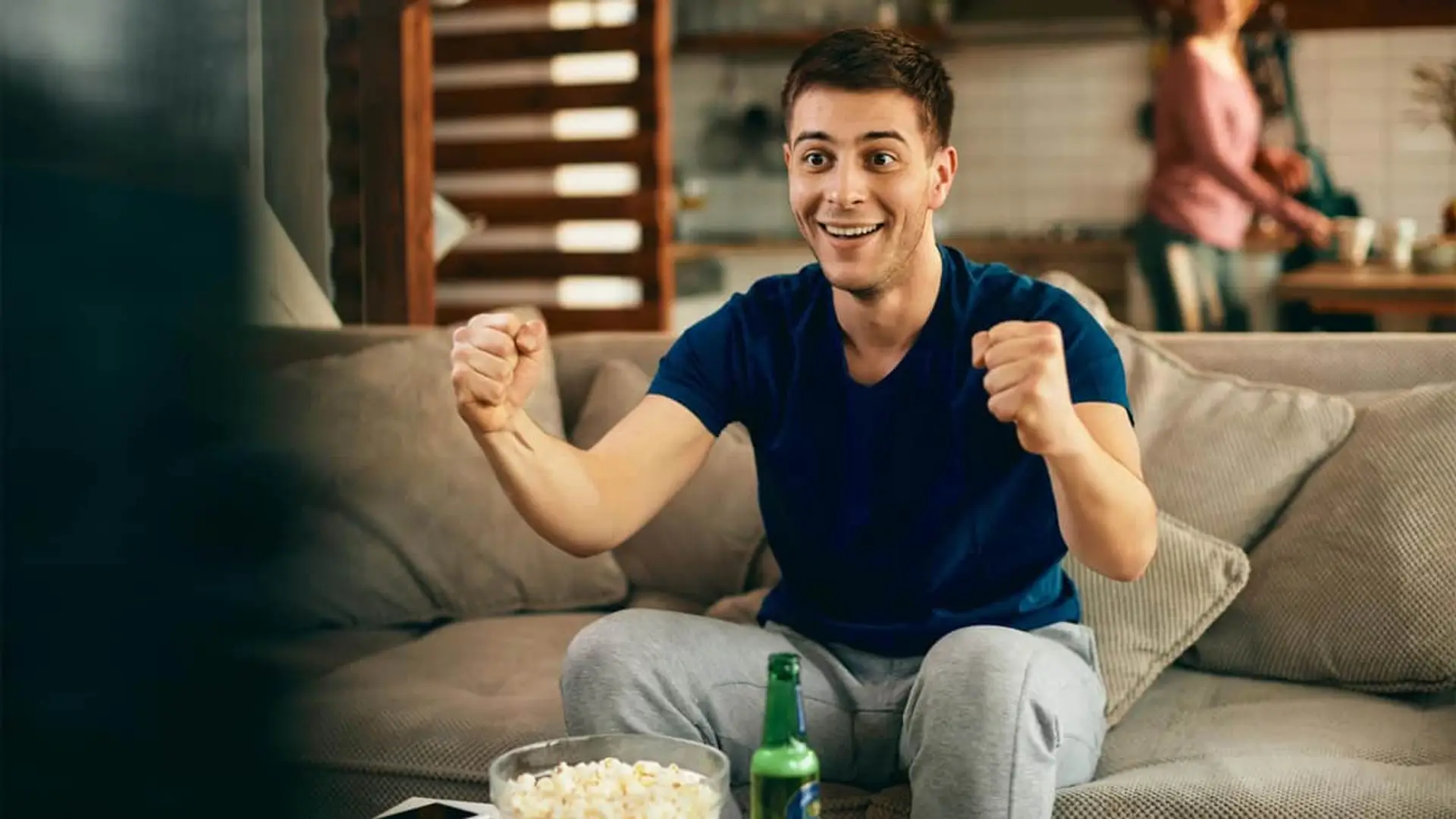 Movistar mete un golazo y lanza un descuento sorpresa para ver el fútbol de LaLiga y Champions Joven aficionado celebrando un gol viendo un partido de fútbol en televisión en casa.