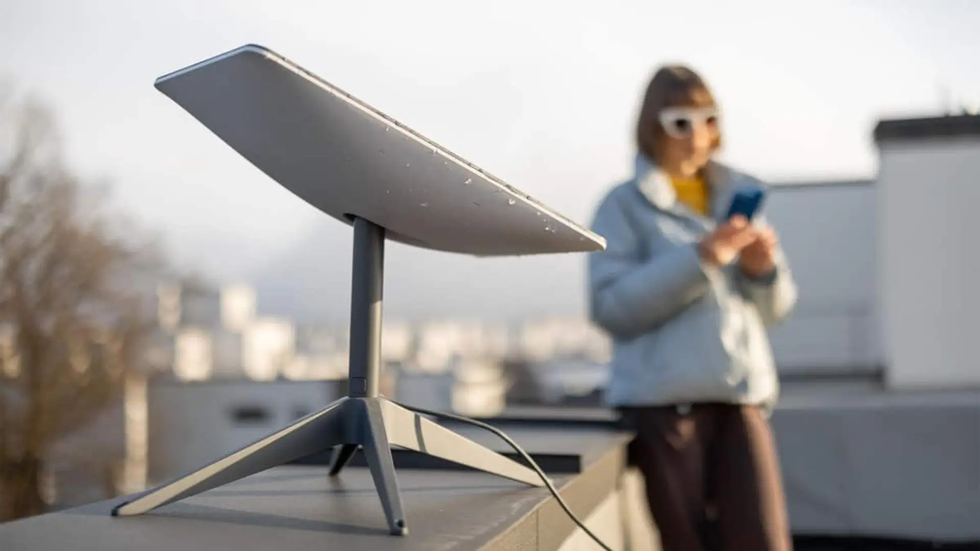 Antena instalada en una azotea con una persona usando un móvil al fondo