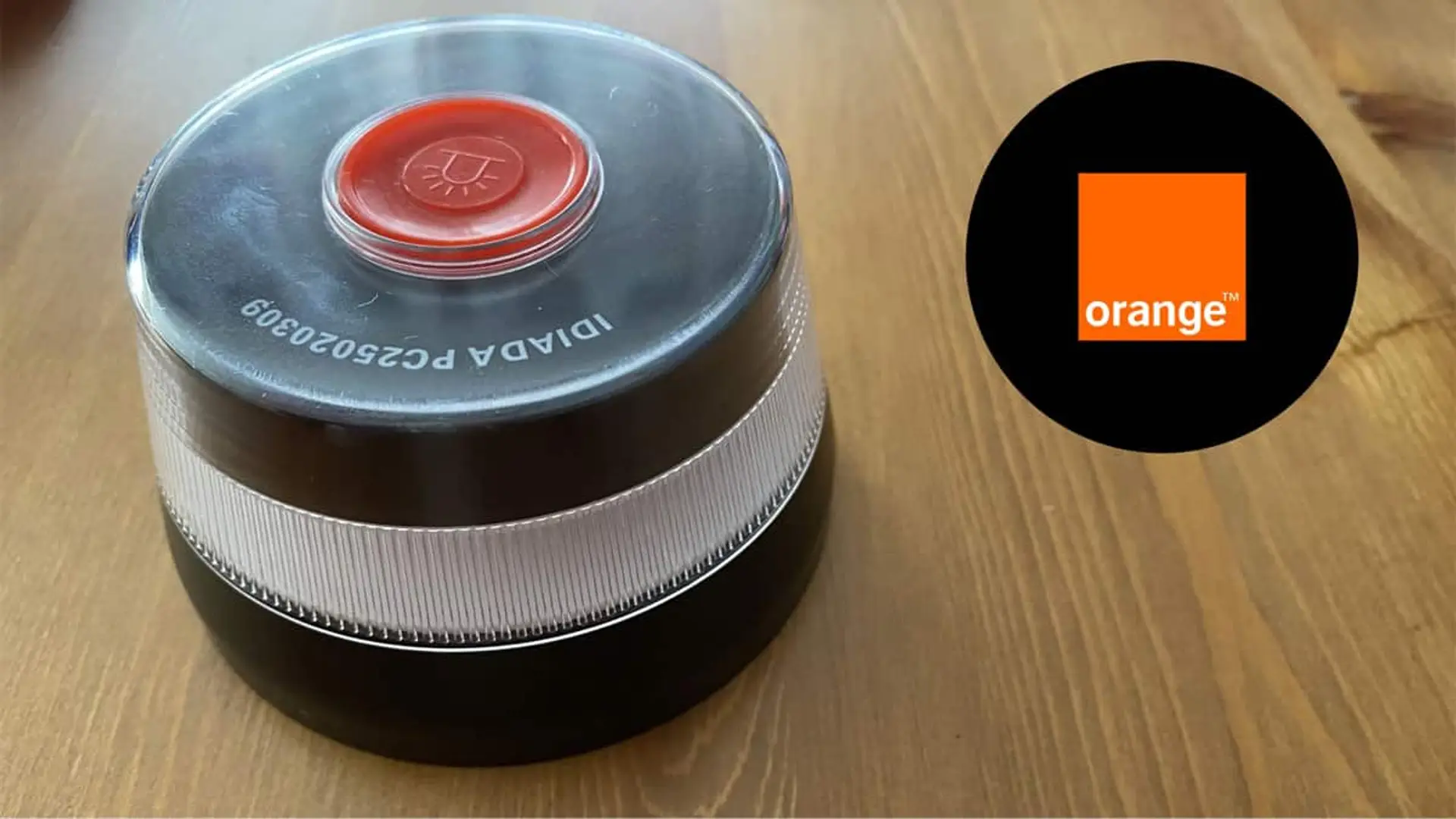 Este supermercado vende la baliza obligatoria V16 con cobertura Orange a precio reducido y con regalo La baliza V16 sobre una esa de madrea y, al lado, el logo de Orange metido en un círculo negro.