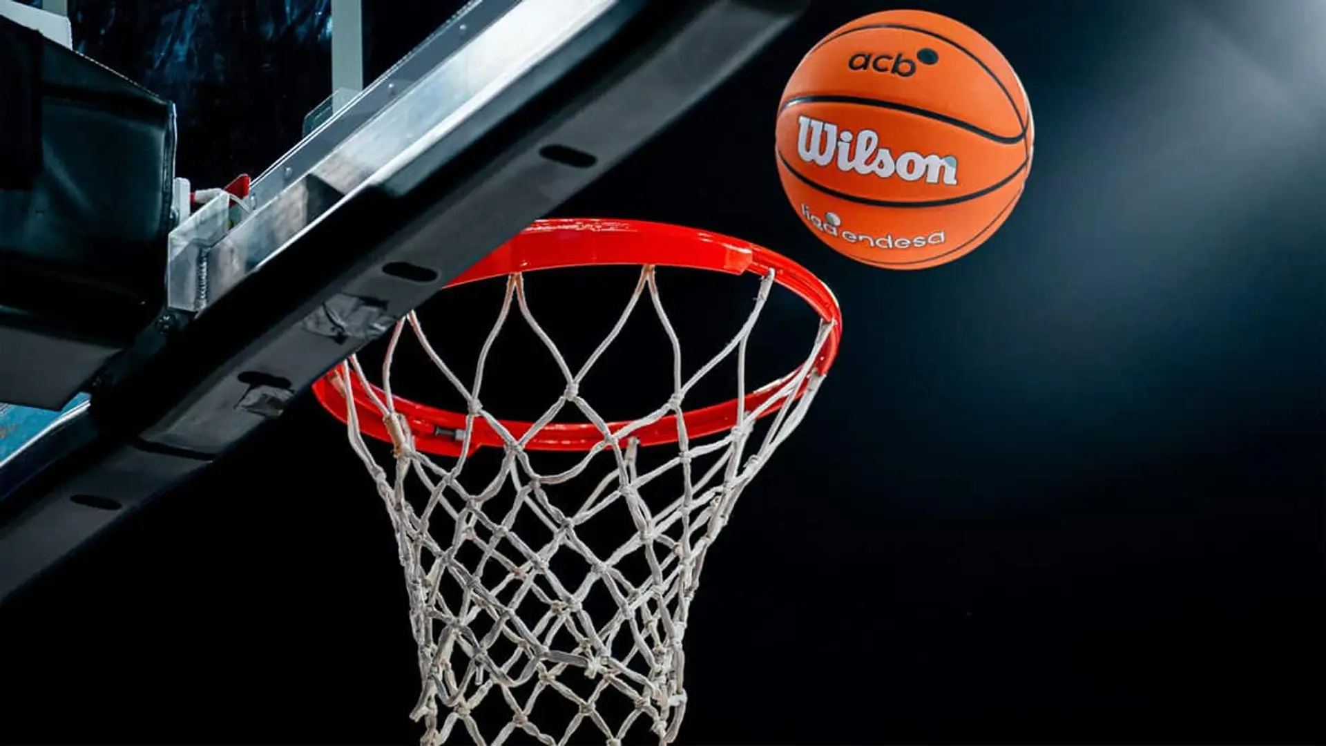 Balón de la ACB acercándose al aro en un partido de baloncesto, con la canasta vista desde abajo.