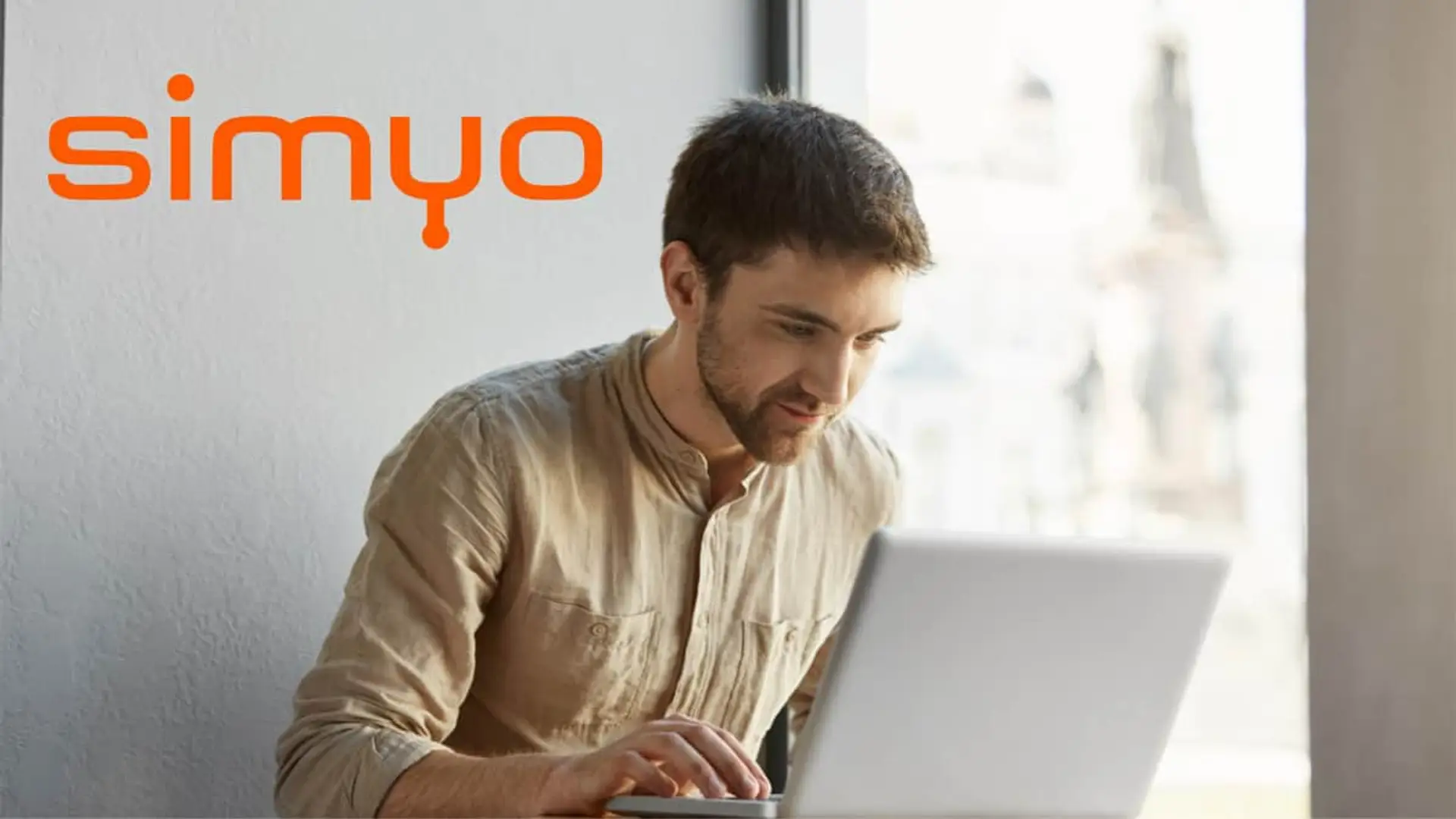Hombre joven trabajando con su ordenador portátil gracias a la conexión de fibra de alta velocidad de la compañía Simyo.