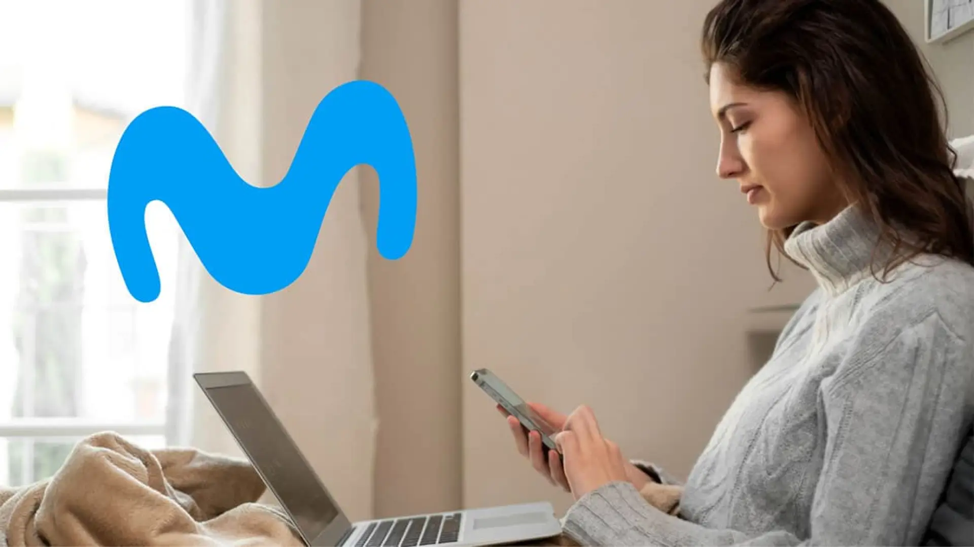 Movistar recupera su fibra más barata en respuesta a la agresiva oferta de Orange Mujer usando su móvil y portátil en el sofá de casa, disfrutando de una buena conexión a internet con la fibra de Movistar.