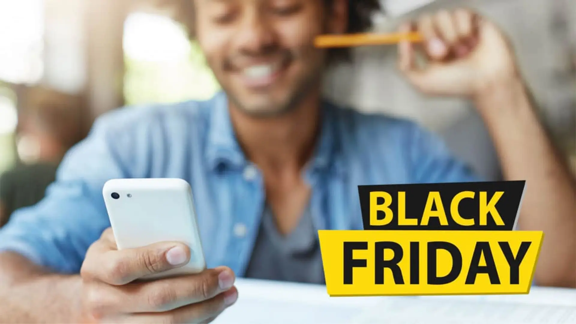Hombre joven y sonriente consultando su smartphone. Aprovecha las ofertas de Black Friday en tarifas de telefonía móvil.