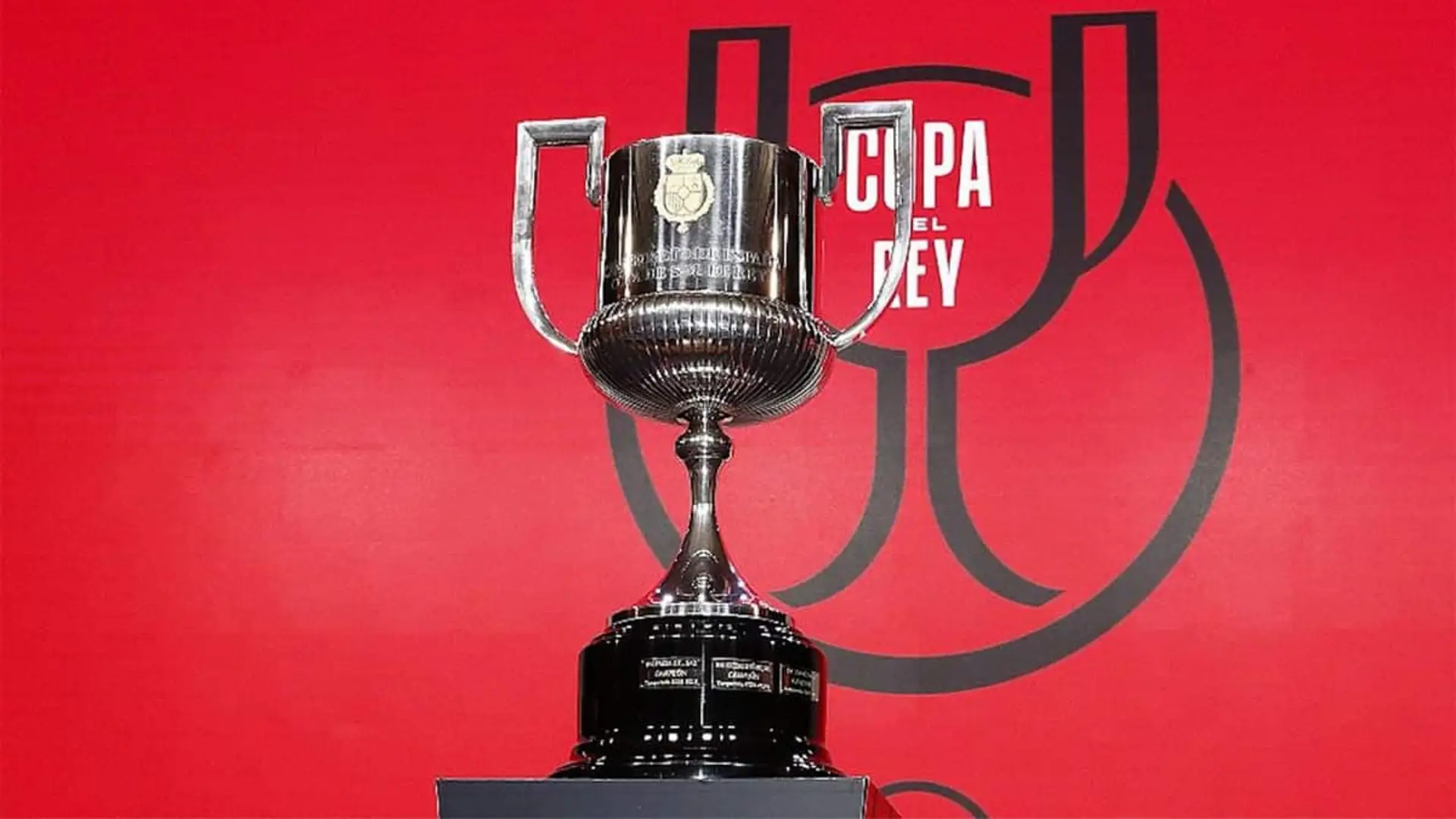 Primer plano del trofeo de la Copa del Rey con fondo rojo.