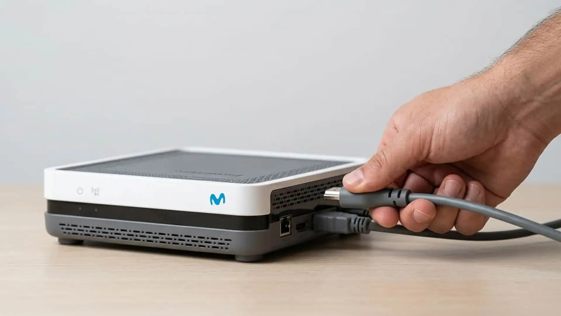 Mano desconectando un cable HDMI a un descodificador de Movistar.