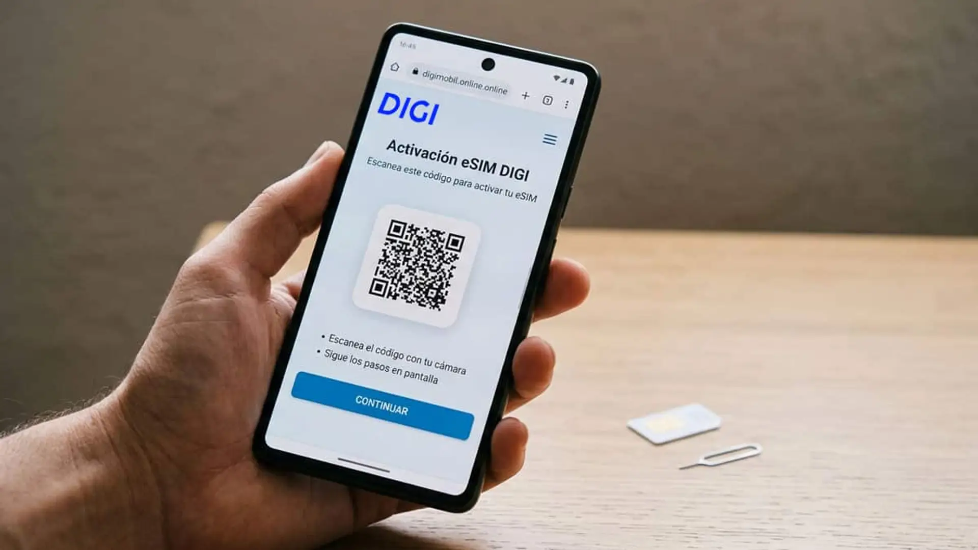 Así puedes tener ya tu eSIM de Digi activa en minutos si te das de alta, sin esperar ningún envío Persona sujetando un móvil con la pantalla de activación de eSIM de DIGI y un código QR