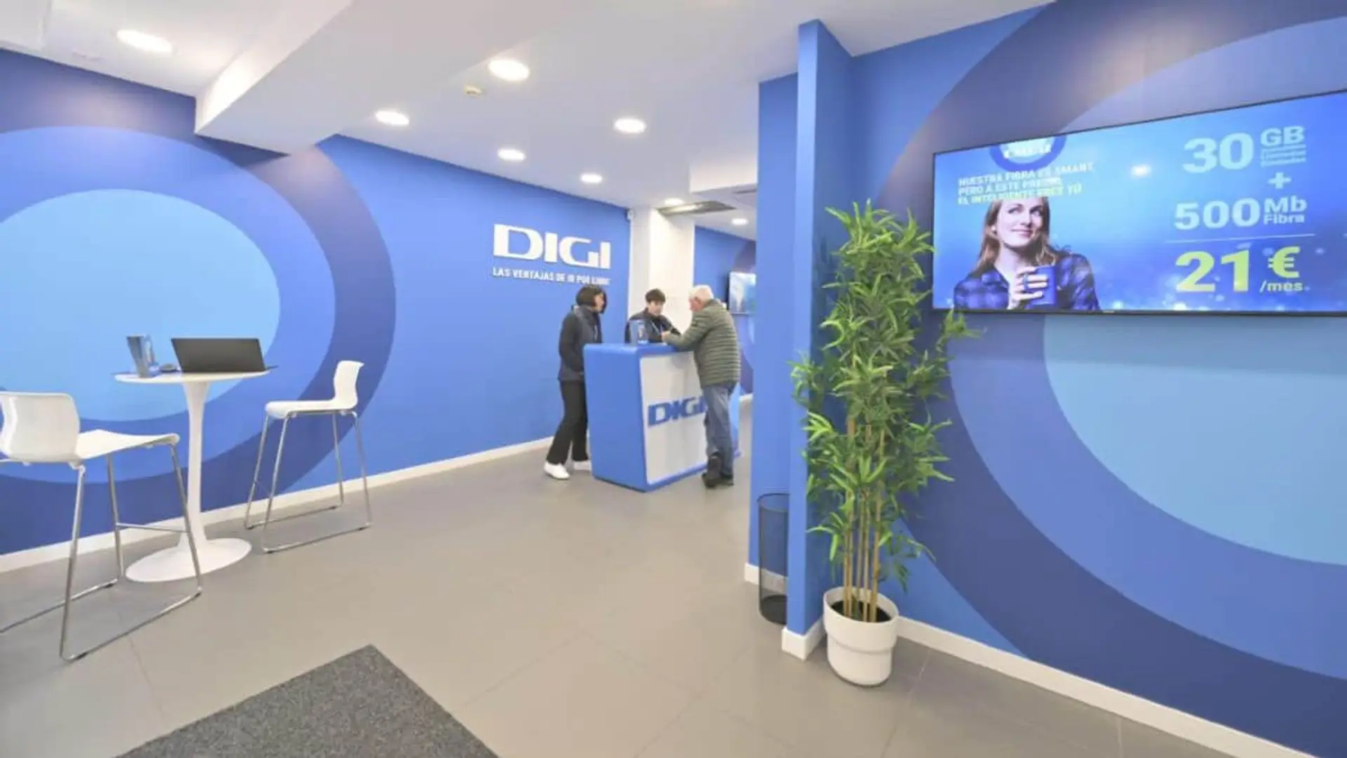 Interior de una tienda oficial DIGI con atención al cliente y oferta de fibra y móvil por 21€ al mes en pantalla.
