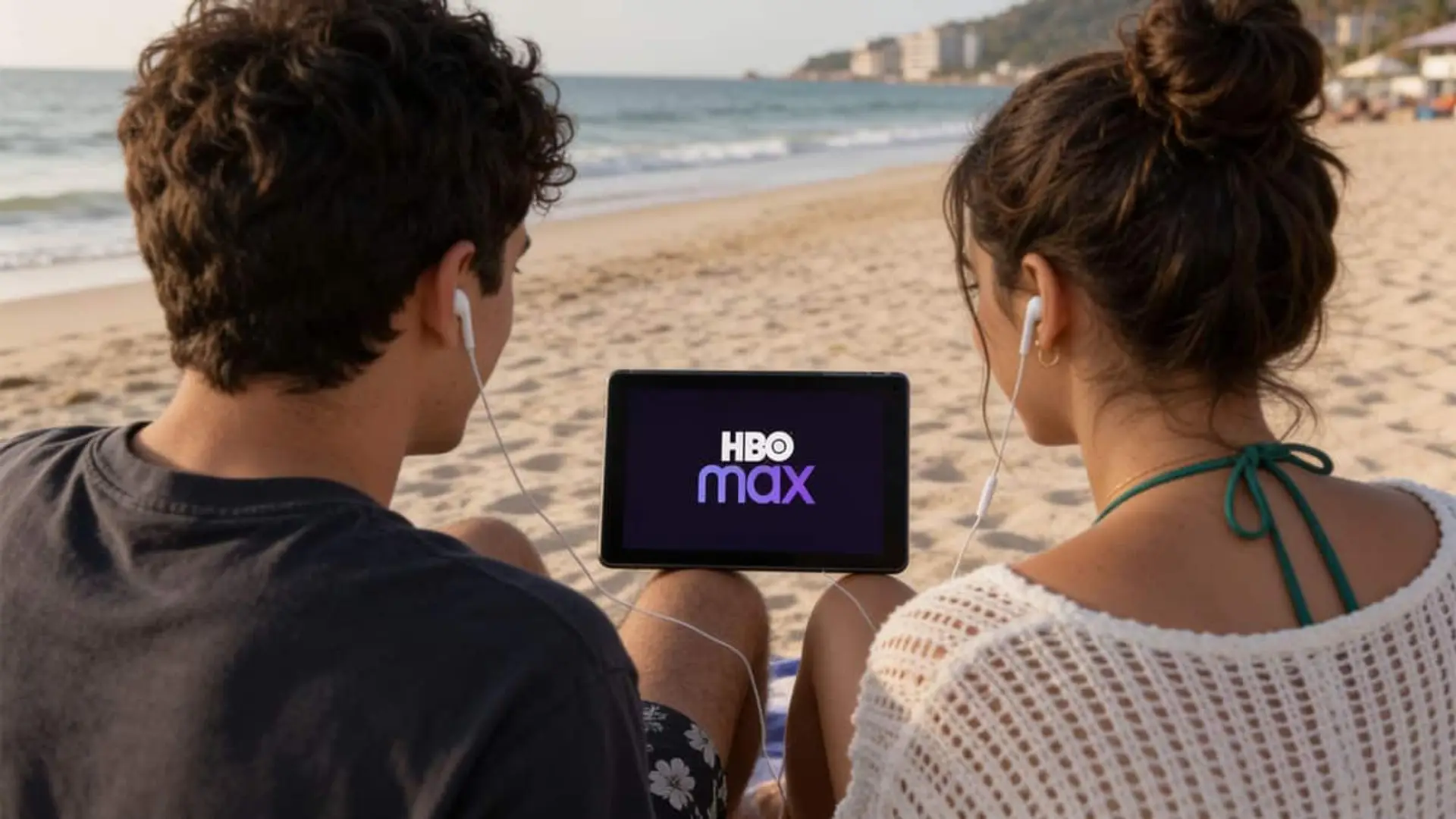 HBO Max carga sus estrenos de julio con Nolan, un spin-off de Big Bang Theory y dos películas españolas Dos personas sentadas en la playa viendo HBO Max en una tablet con auriculares puestos