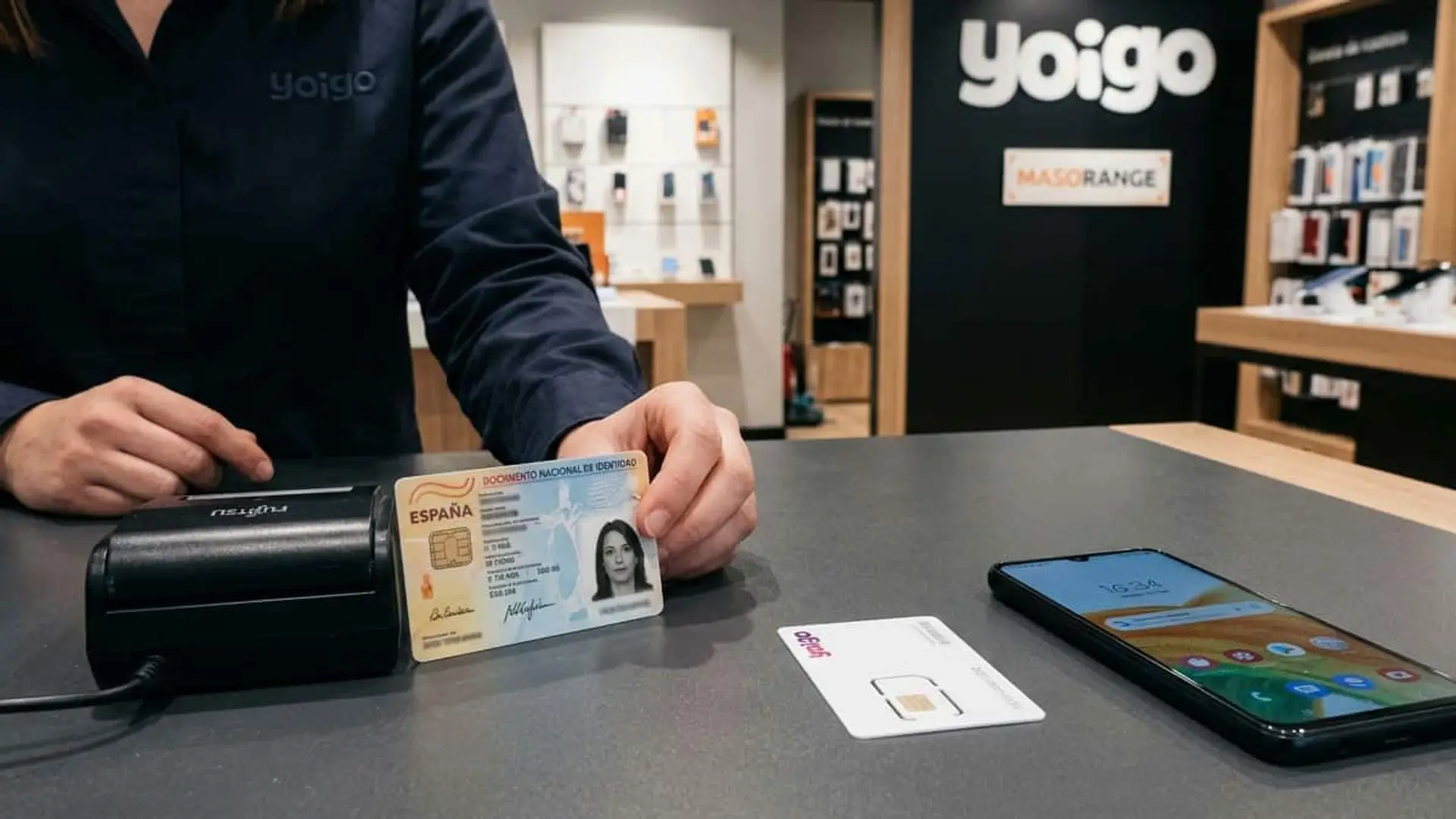 Empleado de una tienda Yoigo mostrando un DNI junto a una tarjeta SIM y un teléfono móvil sobre el mostrador