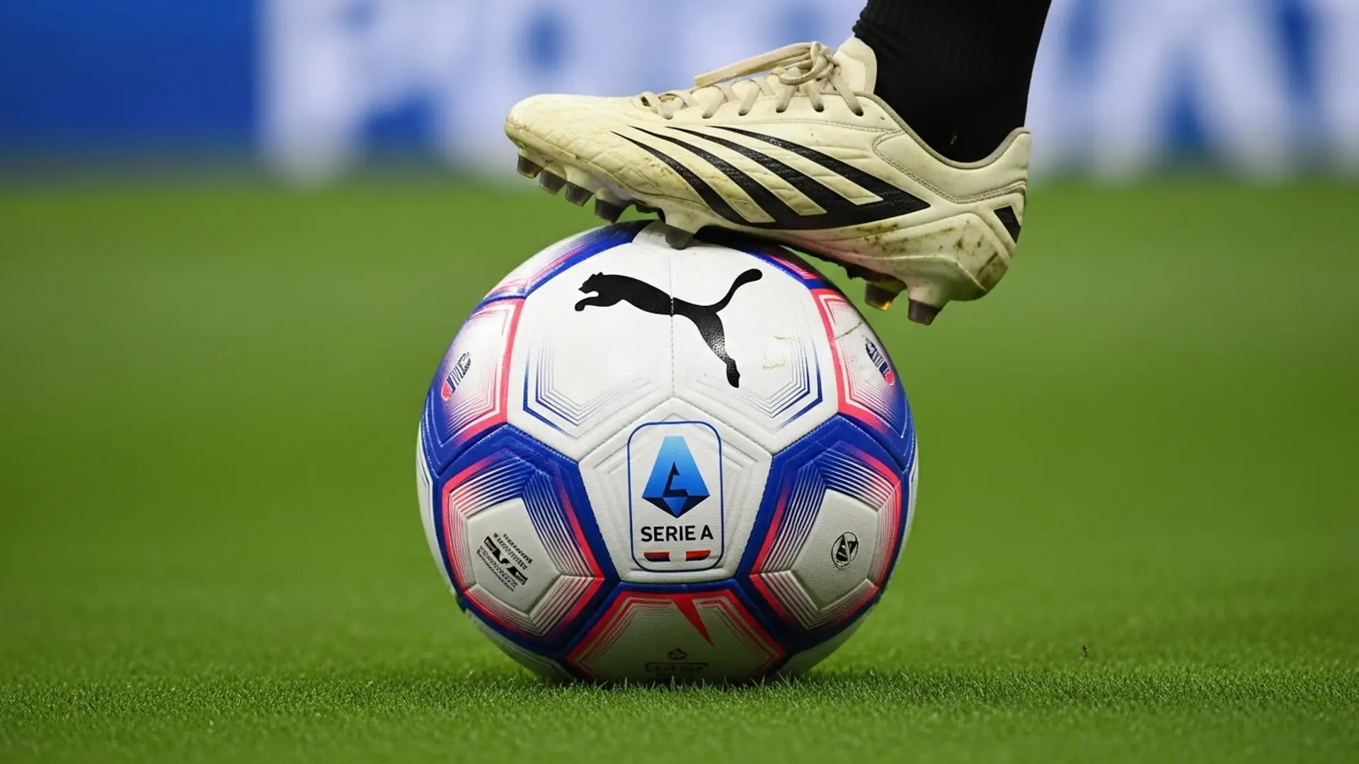 Primer plano de un balón oficial de la Serie A de Puma, con el pie de un futbolista encima, sobre el césped de un estadio.