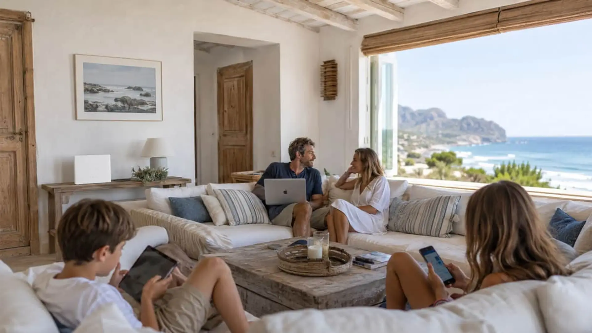 Familia conectada con fibra óptica en casa de verano mediterránea con vistas al mar durante las vacaciones