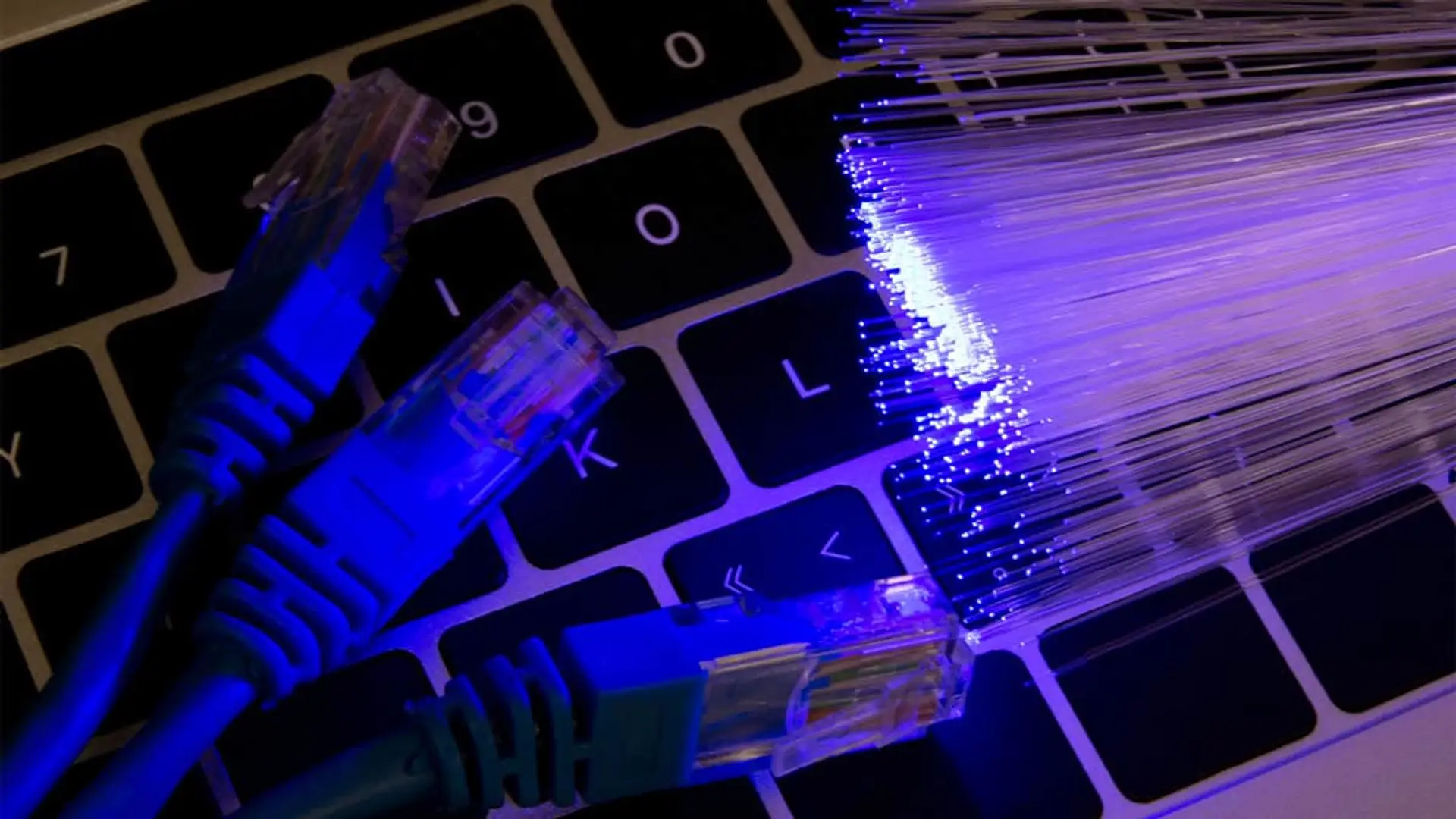 Concepto de la evolución de internet: cables de fibra óptica iluminados junto a cables de red Ethernet.