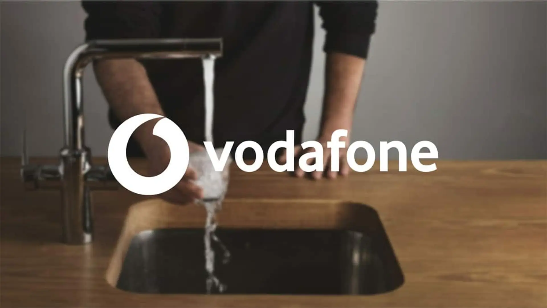 Grifo llenando un vaso de agua con el logotipo de Vodafone sobre la imagen