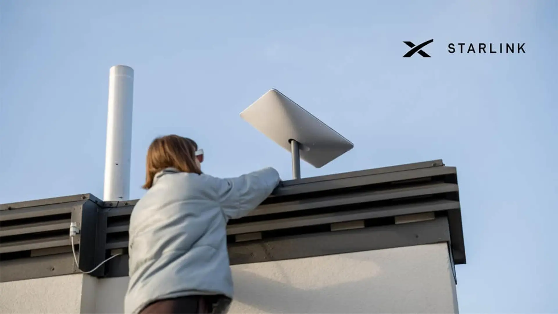 Persona instalando una antena de internet satelital Starlink en el tejado de una vivienda o edificio.