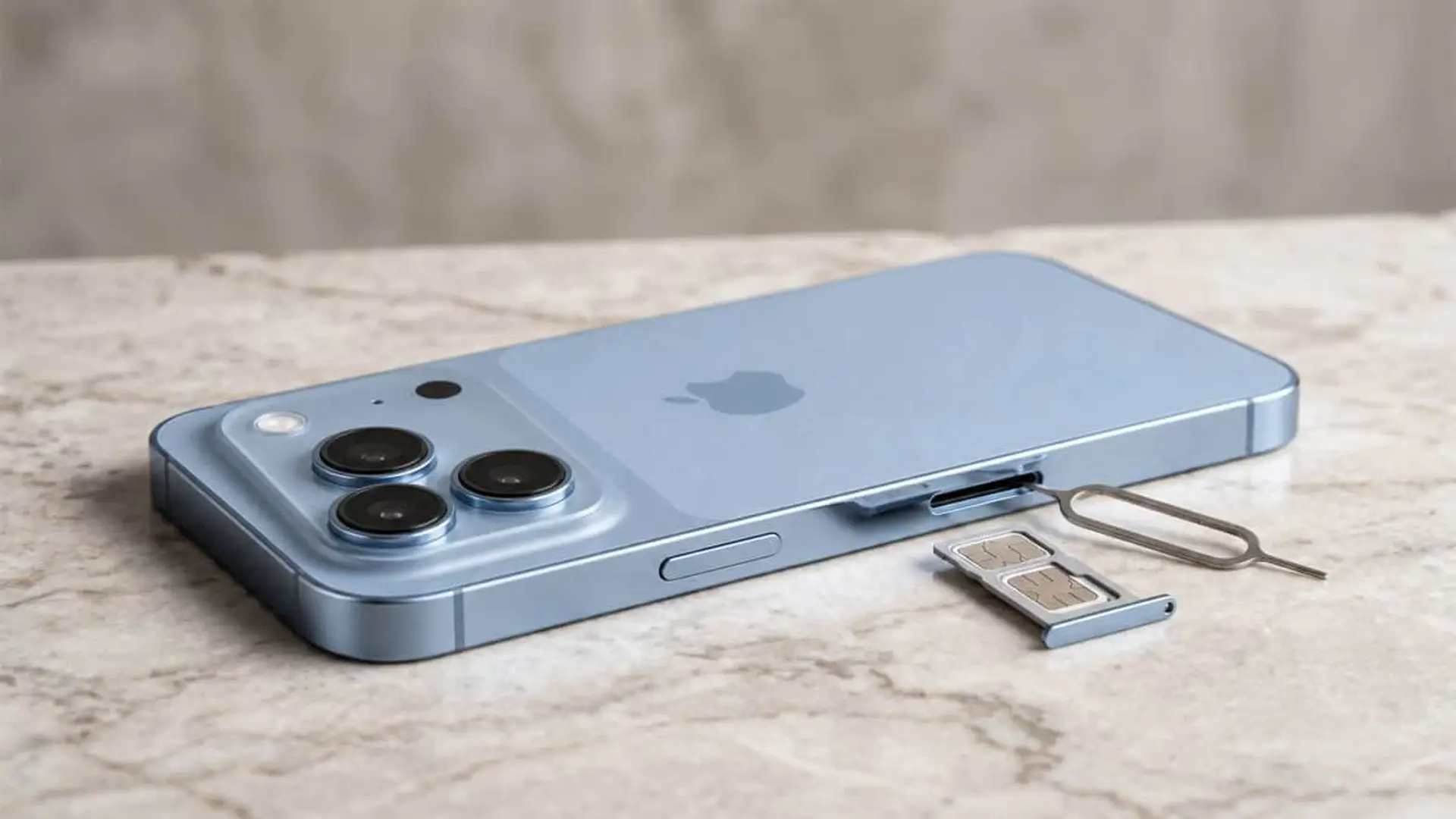 iPhone 18 Pro azul con bandeja SIM extraída y herramienta de expulsión sobre una superficie de mármol.
