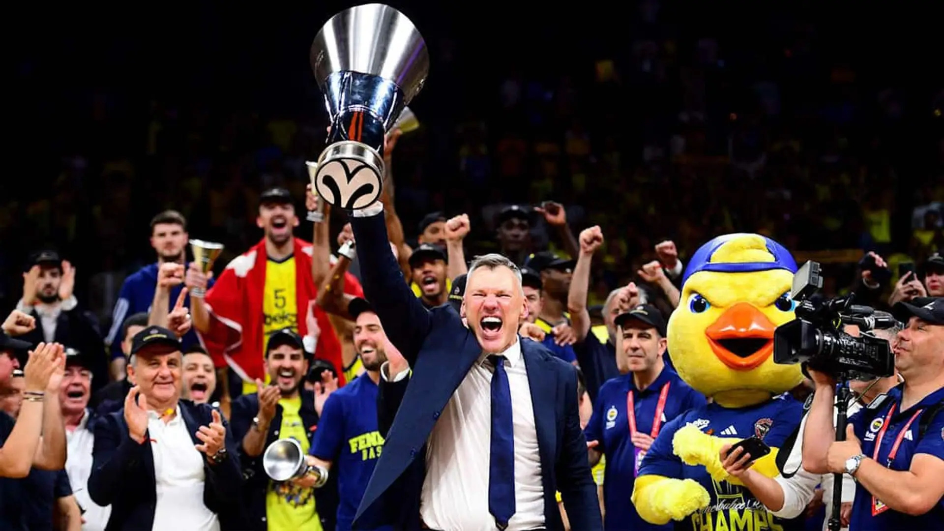 Sarunas Jasikevicius, entrenador del Fenerbahçe, levantando un trofeo mientras el equipo celebra alrededor en la pista
