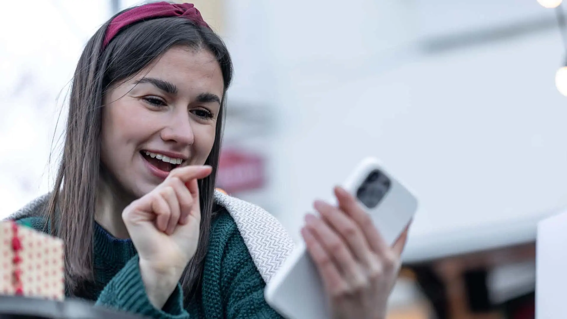 Joven sonriendo mientras utiliza su smartphone para comunicarse.