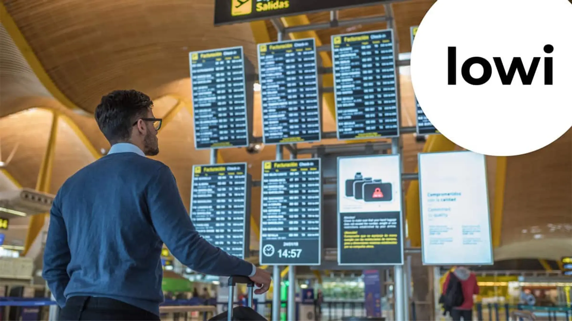 Hombre consultando pantallas de vuelos en un aeropuerto en el contexto de tarifas móviles y roaming de Lowi.