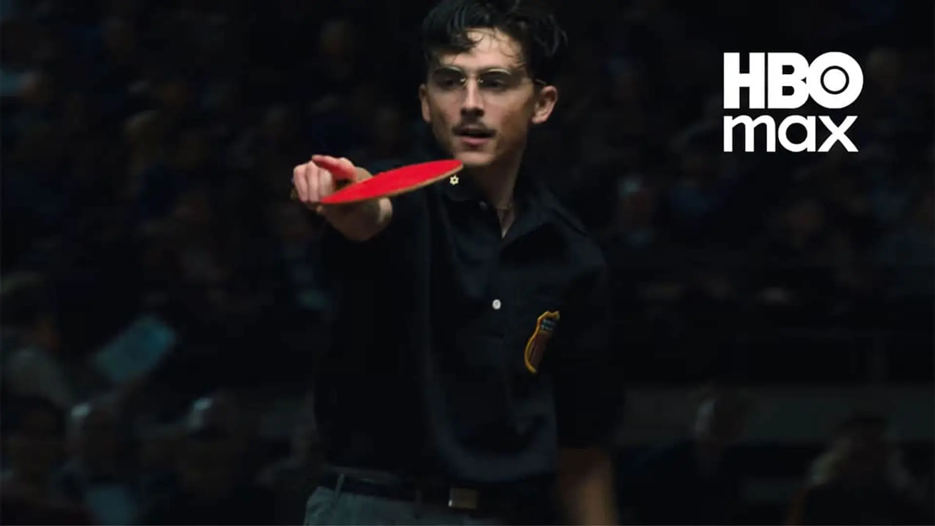 Escena de Timothée Chalamet jugando al ping pong en la película Marty Supreme con el logotipo de HBO Max.