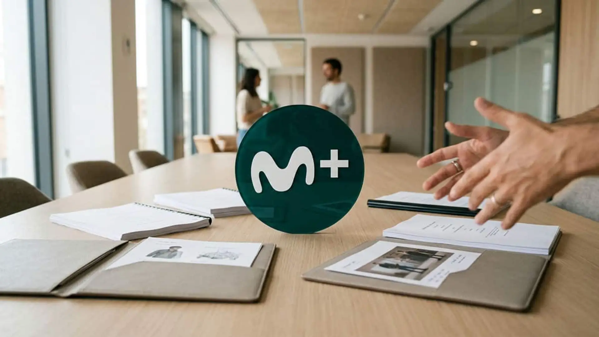 Movistar Plus quiere más audiencia sin perder su sello: esta es la estrategia con la que busca sus próximas series Mesa de reunión con materiales de trabajo y el logotipo de Movistar Plus+ en el centro de la imagen
