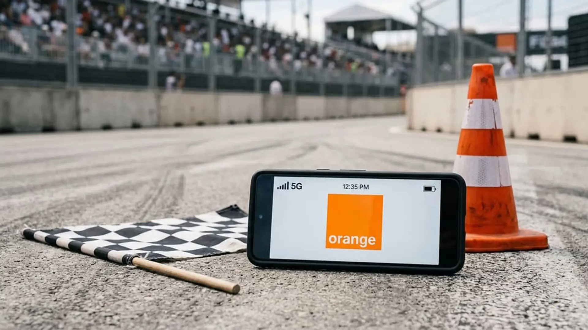 Móvil con el logo de Orange junto a una bandera a cuadros y un cono en un circuito de carreras