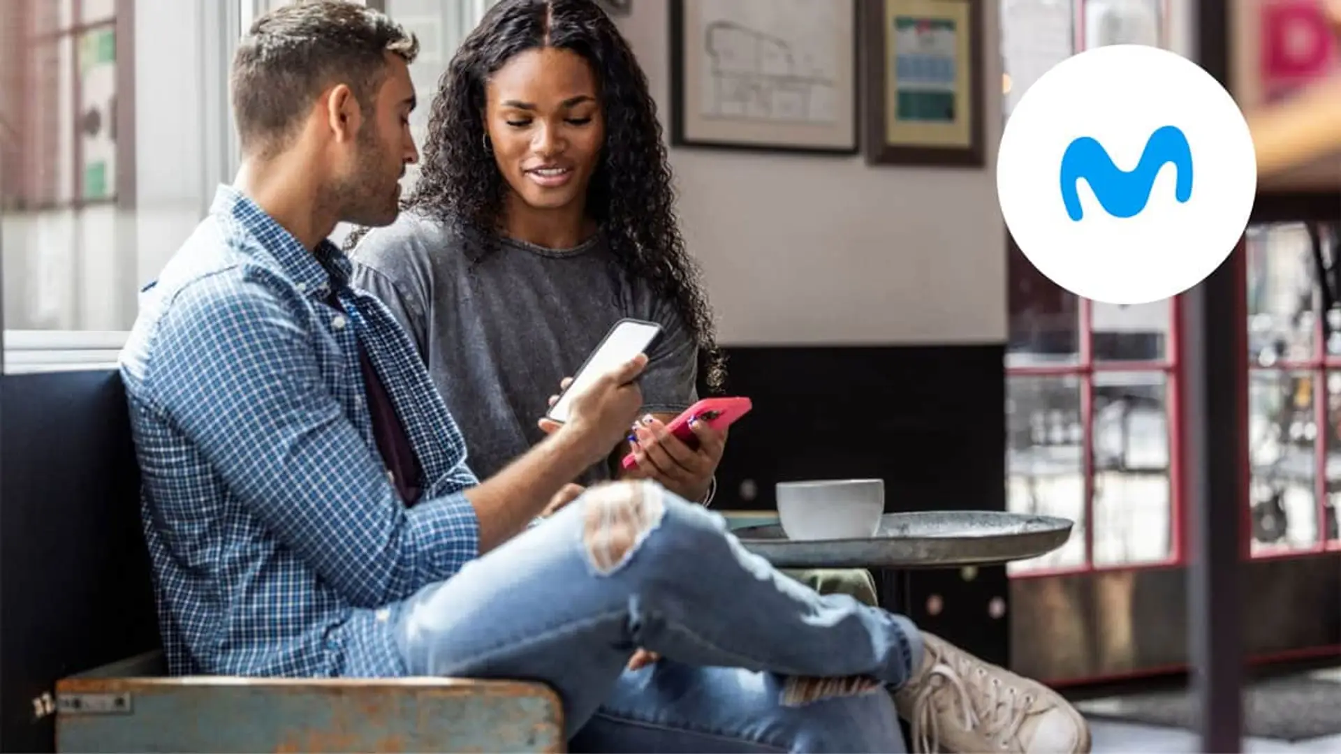 Movistar sorprende a sus clientes con esta mejora en una de sus mejores tarifas móviles Pareja joven compartiendo pantalla del móvil en cafetería junto al logo de Movistar.