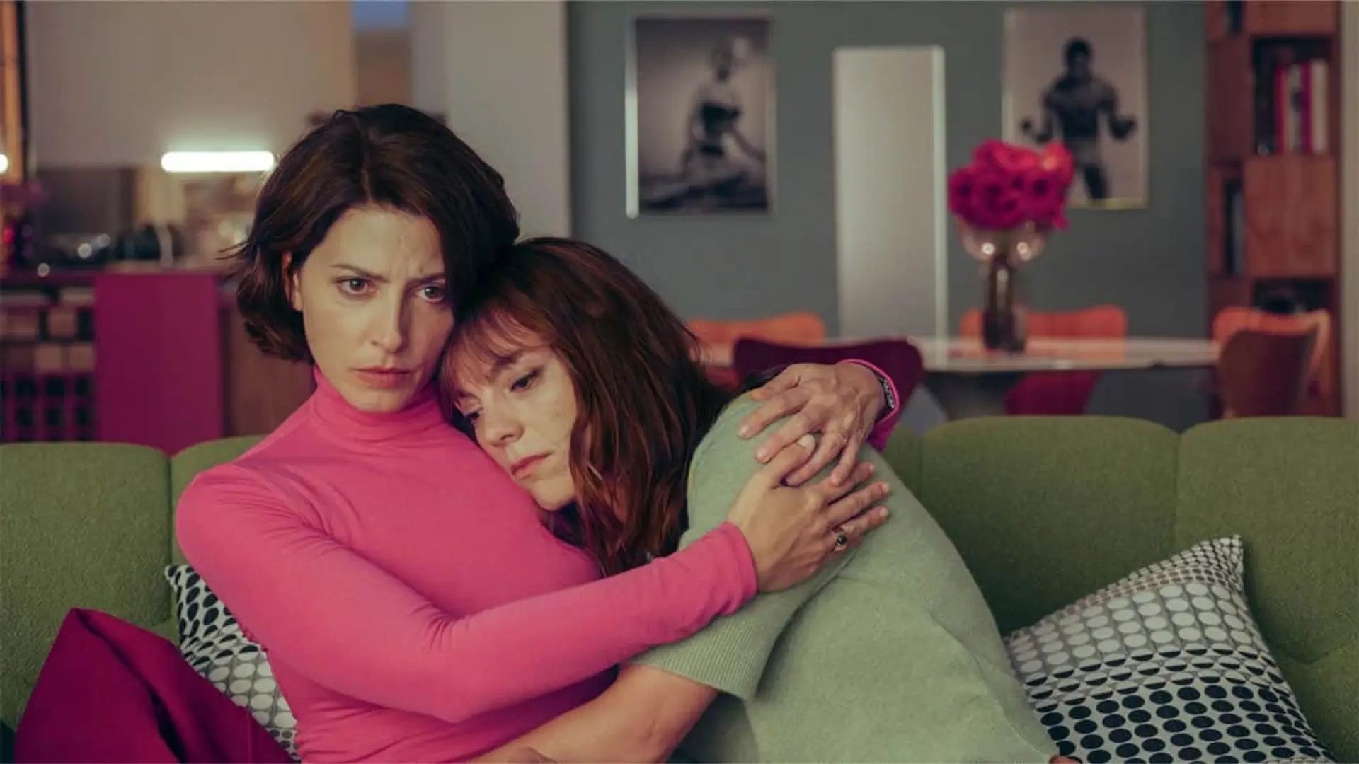 Dos mujeres abrazadas en un sofá verde en una escena dramática de Amarga Navidad