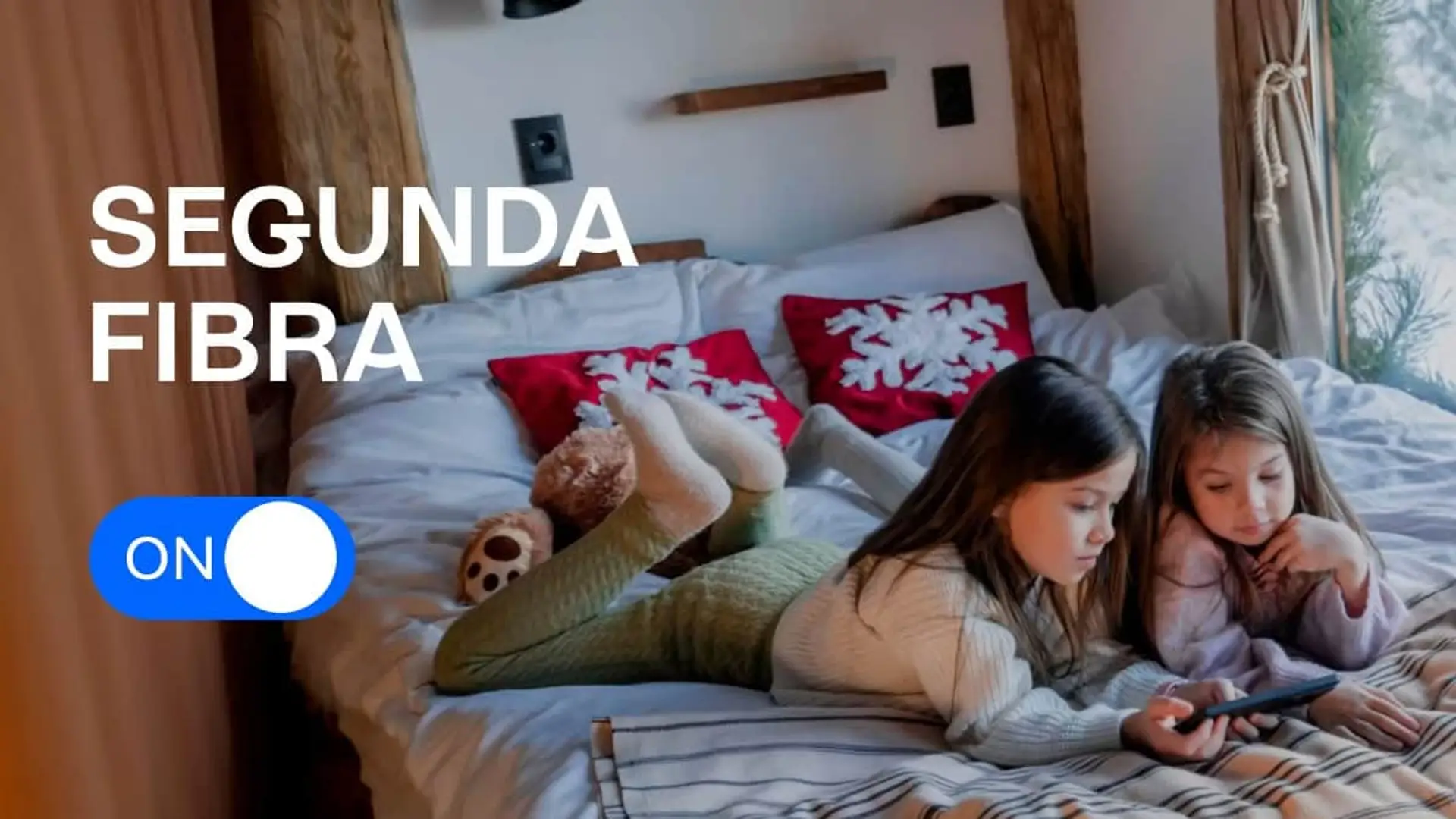 Movistar tiene fibra para tu segunda residencia desde 0,50€ al día y solo pagas cuando la usas, pero hay una condición Dos niñas usando un móvil en una cama de casa rural con el texto Segunda Fibra y el botón ON de Movistar.