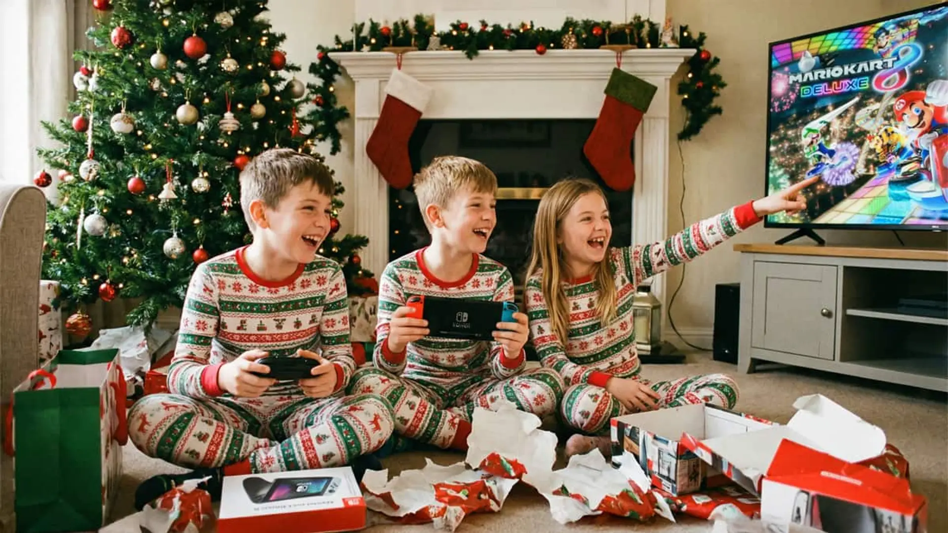 Las Blue Xmas de Movistar adelantan los regalos de Navidad: rebaja en fibra, Nintendo Switch 2 y iPhone 17 Niños jugando a la Nintendo Switch en Navidad en el salón, rodeados de regalos y árbol navideño