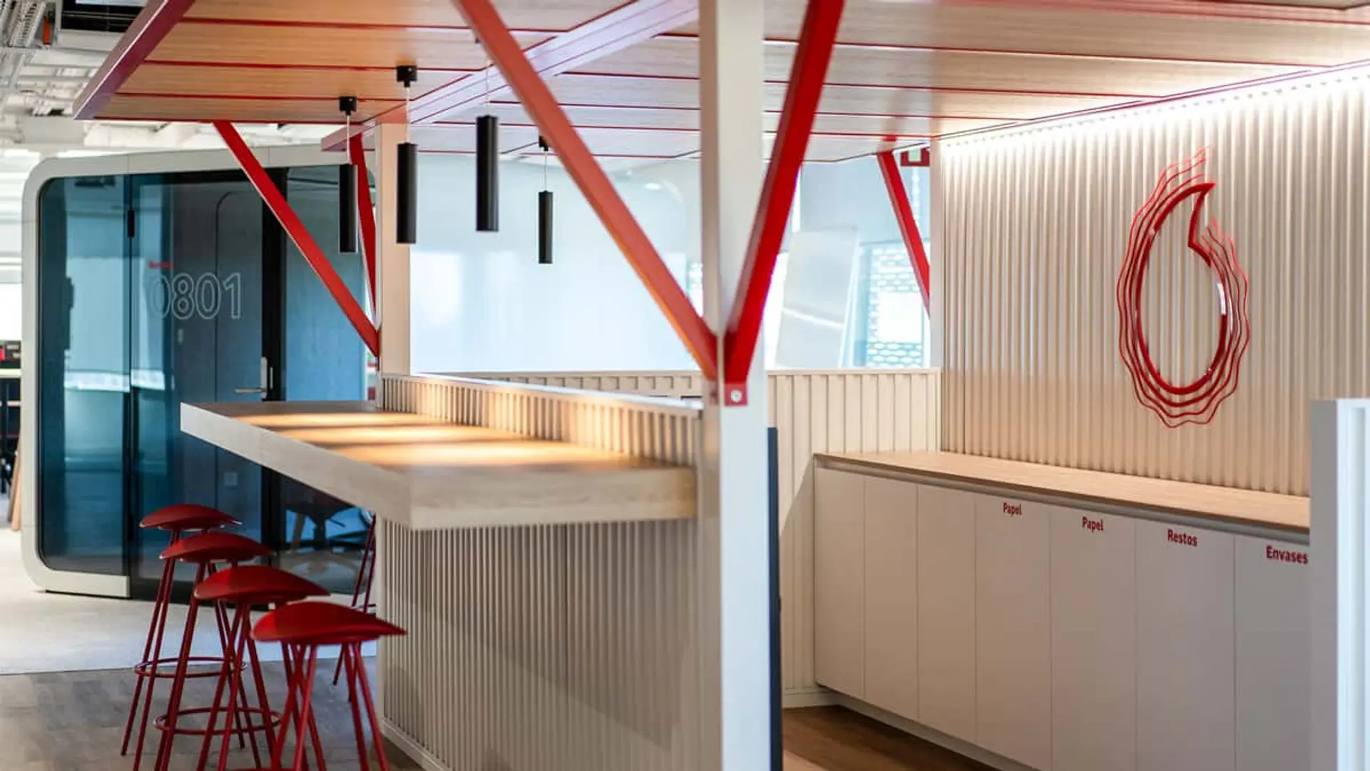 Interior de las modernas oficinas corporativas de Vodafone España, con el logo de la compañía en la pared.